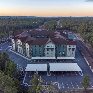 Aerial view of a resort surrounded by a forest during sunset, featuring a spacious parking area.