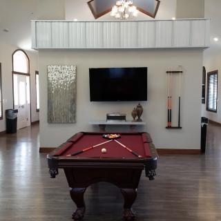 A modern game room featuring a pool table and a television on the wall.