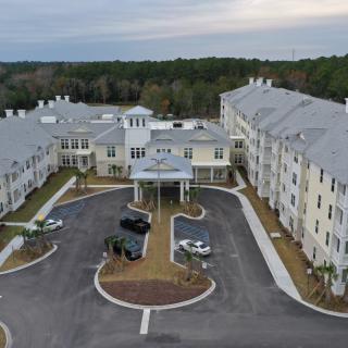 Aerial view of a large building complex with surrounding parking area and landscaping.