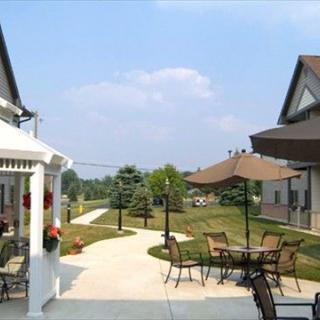 A serene outdoor patio area with tables and chairs under umbrellas, set between two houses with a landscaped pathway.