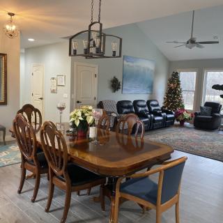 An open floor plan featuring a dining area with wooden furniture and a nearby living room decorated with a Christmas tree.