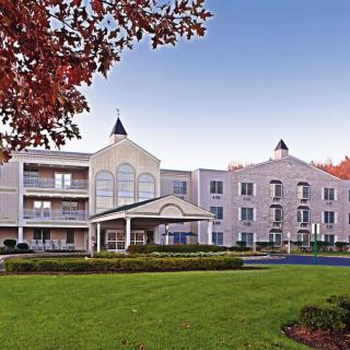 A hotel building with a well-maintained lawn, surrounded by autumn foliage.