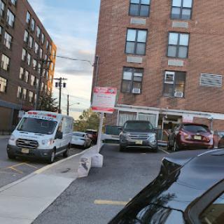 A view of a parking lot with various vehicles beside a brick building in an urban setting.