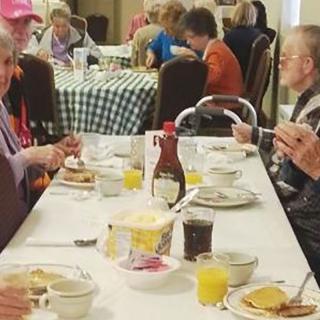 A group of elderly individuals enjoying breakfast together in a communal setting.