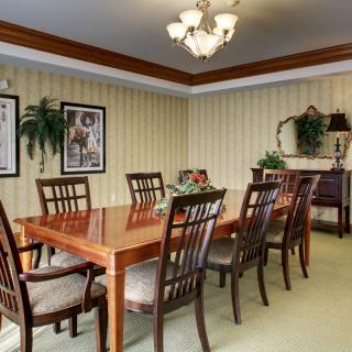 A well-decorated dining room with a wooden table and chairs, illuminated by a chandelier.