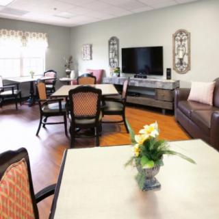 A cozy living room with tables, chairs, a sofa, and a television.