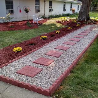 A beautifully designed garden path featuring red stepping stones and vibrant flowers.