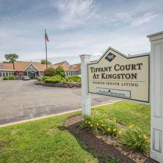A sign for 'Tibasy Court at Kingston Senior Living' in front of a residential building and landscaped driveway.