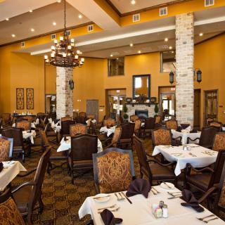 An elegant dining room setup with neatly arranged tables and chairs, complemented by warm lighting.