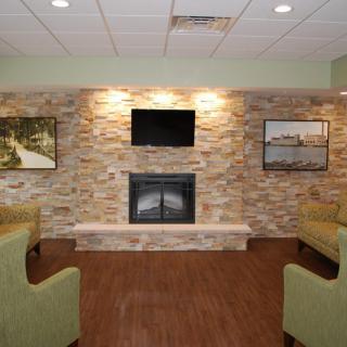 A cozy living room with a stone fireplace, television, and comfortable seating.