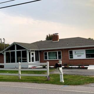 A brick building with large windows, possibly an office or commercial space, featuring a sign on the front.