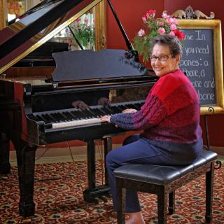 A person seated at a grand piano, ready to play indoors.