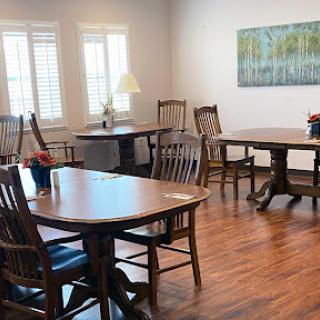 A cozy gathering space featuring wooden tables and chairs, illuminated by natural light.