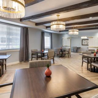 A modern dining room with wooden tables, chairs, and elegant chandeliers.