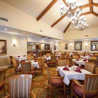 A well-appointed dining room with elegant chandeliers and neatly set tables.