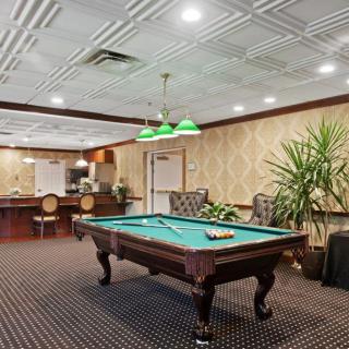 A stylish billiard room featuring a pool table, elegant lighting, and cozy seating arrangements.