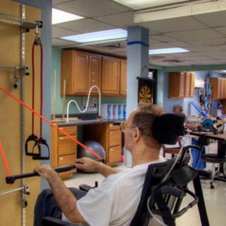 A person in a wheelchair using exercise equipment during a physical therapy session.