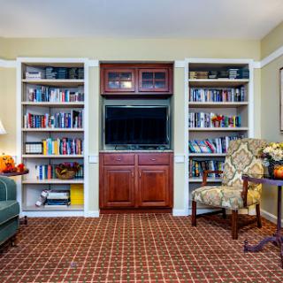 A cozy living room featuring bookshelves filled with books, a comfortable chair, and a television.