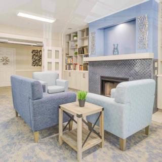A cozy living room with blue chairs, a fireplace, and built-in bookshelves.