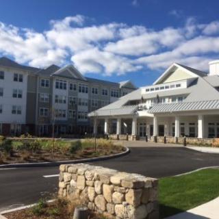 A modern hotel building with a welcoming entrance under a partly cloudy sky.