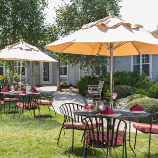 Outdoor dining area with tables and umbrellas in a garden setting.
