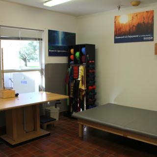 A therapy room equipped with a table, exercise equipment, and a bed.