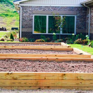 Raised garden beds prepared for planting in a neatly landscaped backyard.