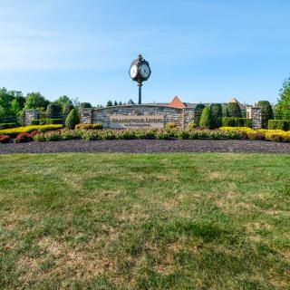 A well-maintained public garden with a prominent clock tower in the background.