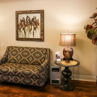 A cozy living room setup featuring a patterned sofa, a stylish lamp, and an abstract artwork on the wall.