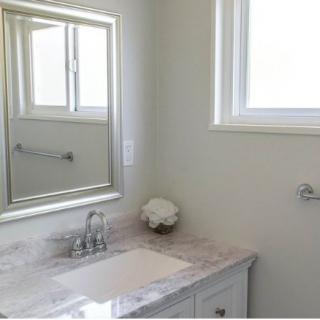 A minimalist bathroom with a marble countertop and a large mirror.