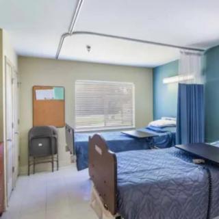A hospital room with two patient beds and privacy curtains.