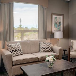 A cozy living room with a beige sofa, patterned cushions, and a coffee table with flowers.