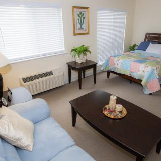 A cozy room featuring a bed, couch, and coffee table with decorative items.