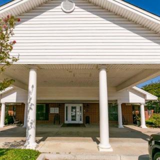 A building entrance with white columns and a gabled roof.