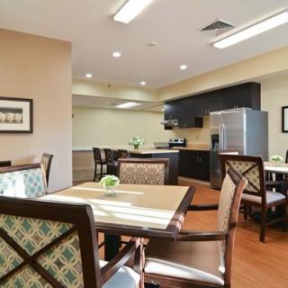 A modern dining area with a kitchen, featuring chairs and tables.