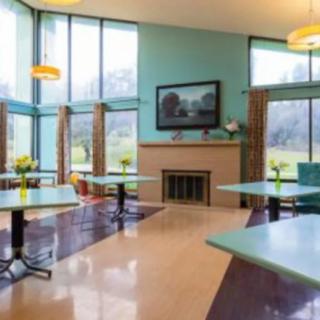 A modern dining area with large windows and a fireplace.