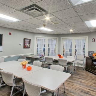 A well-lit conference room with arranged tables and chairs, decorated with flowers and small pumpkins.