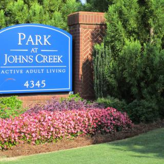 A sign for Park at Johns Creek surrounded by flowers and greenery.