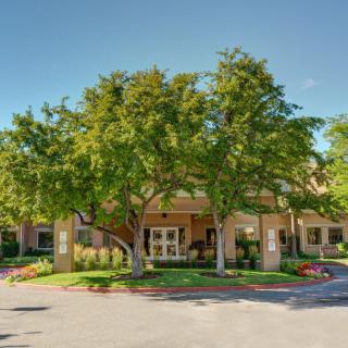 A welcoming building entrance surrounded by lush trees and landscaped greenery.