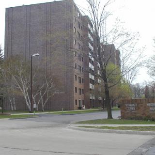 A multi-story apartment building situated at the corner of a residential street, surrounded by trees.