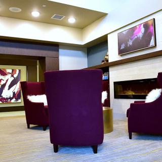 A modern seating area with purple chairs and a fireplace, decorated with contemporary artwork.