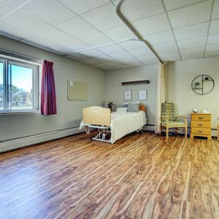 A well-lit hospital room designed for patient comfort, featuring a bed, chair, and storage.