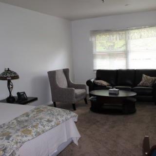 A cozy living room with a sofa, armchair, table, and lamp near a large window.