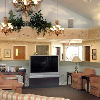 A cozy living room setting featuring comfortable seating, a large television, and elegant lighting.
