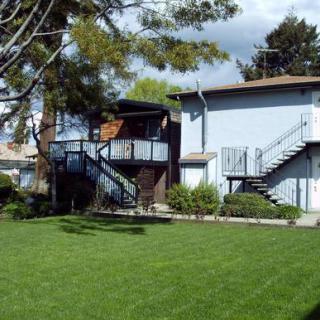 Exterior view of a multi-unit residential building with stairs and well-maintained lawn.