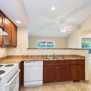 A modern kitchen featuring wooden cabinets, a tiled countertop, and standard appliances.