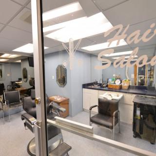 An interior view of a hair salon with chairs and styling stations visible through a glass door.