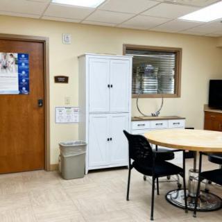 A small office meeting room with a table, chairs, and storage cabinets.