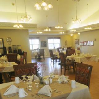 A well-lit dining room with neatly arranged tables and chairs.