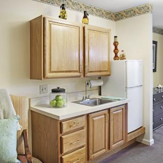 A small kitchen area featuring wooden cabinets, a white refrigerator, and a sink with countertop space.